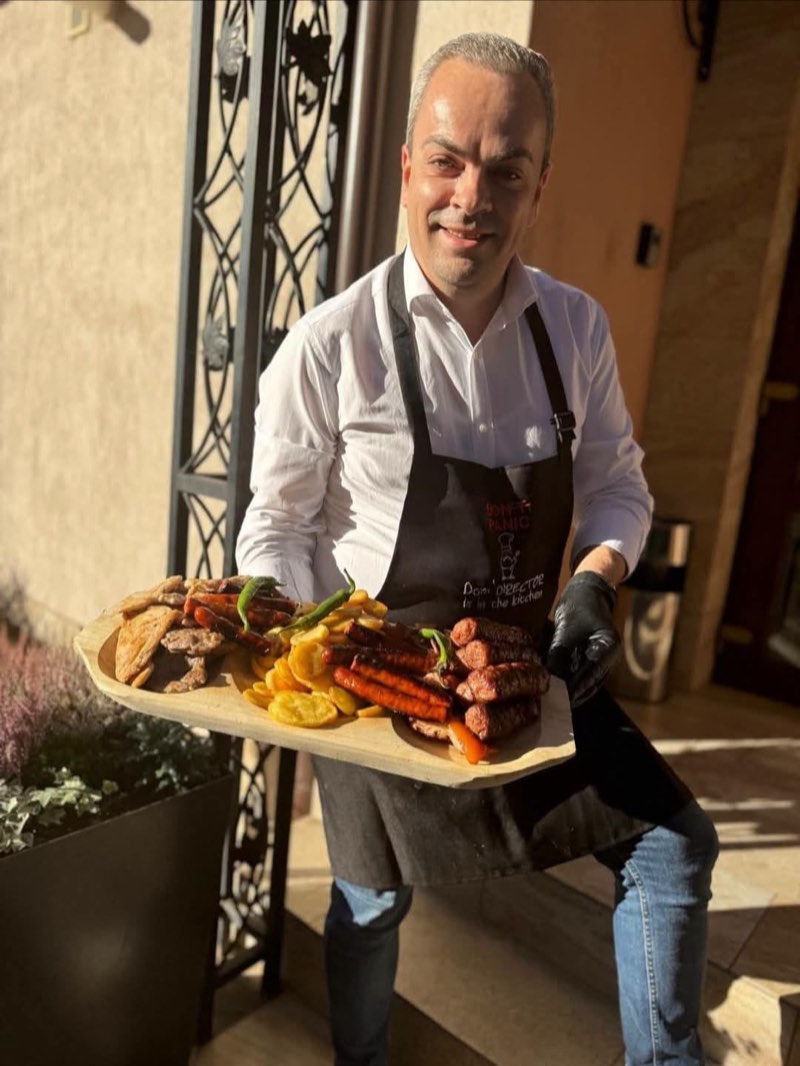 Gazda restaurantului cu un platou de lemn cu mici și grătar