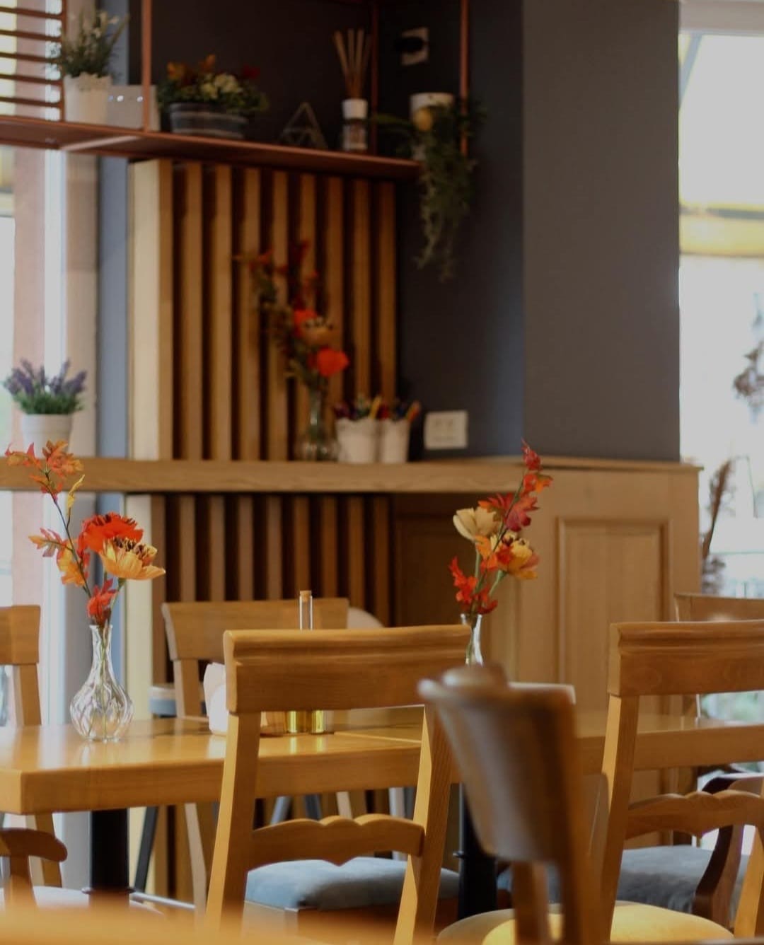 Mese de lemn cu flori în vaze, în sala restaurantului CREMA