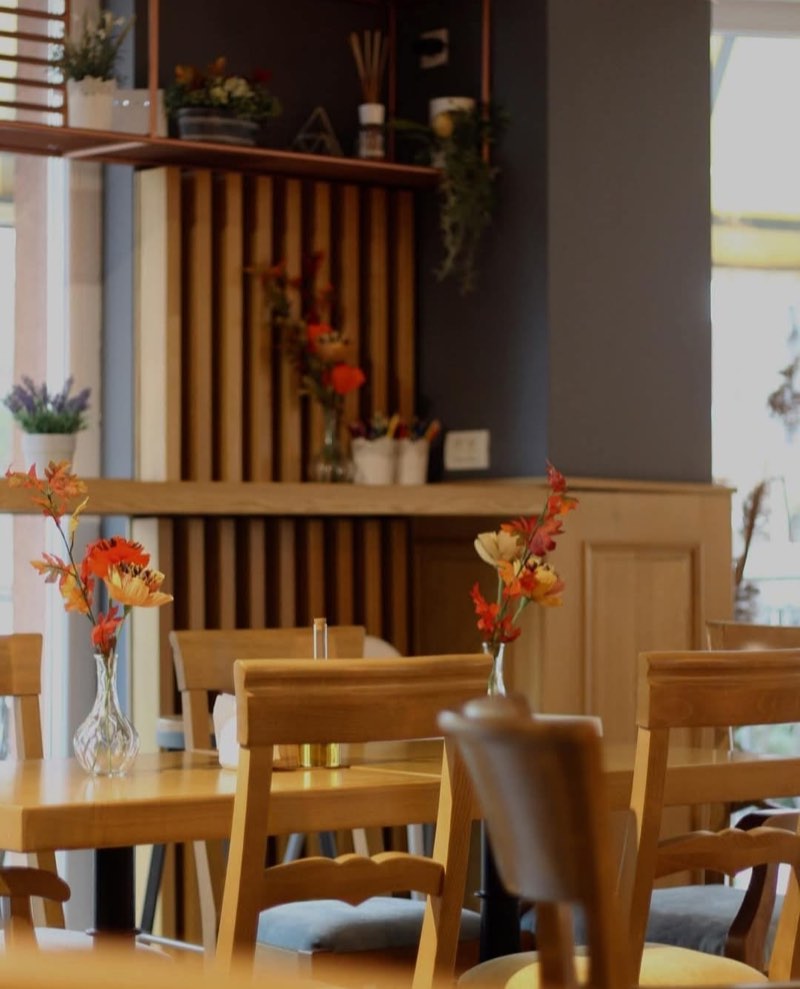 Mese de lemn cu flori în vaze, în sala restaurantului CREMA
