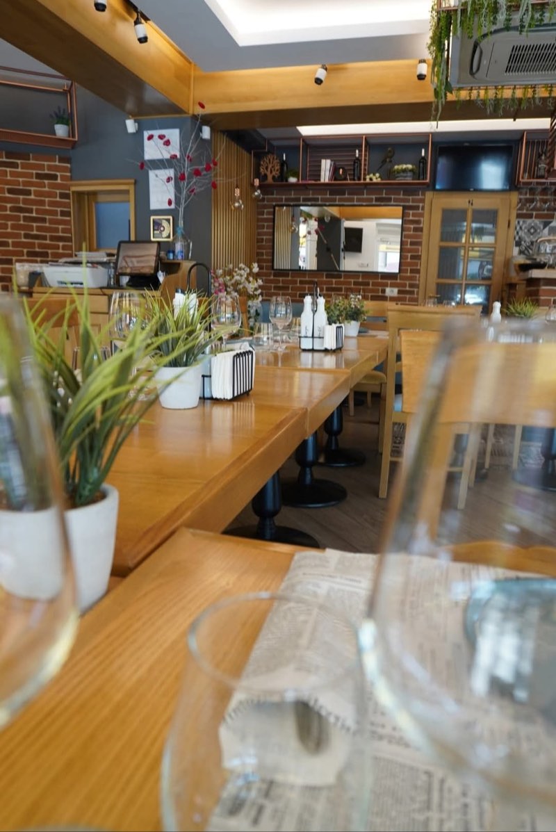 Sala restaurantului CREMA cu mese de lemn, zid de cărămidă și rafturi decorative