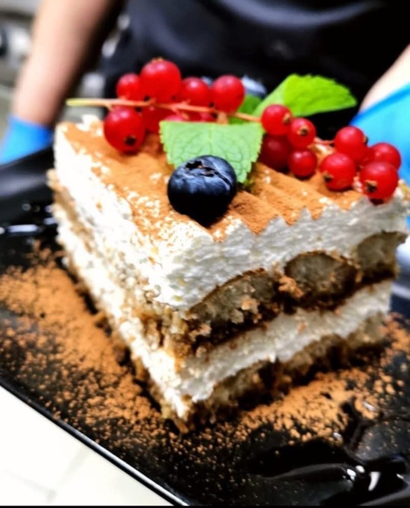 Felie de tiramisu cu cacao, coacăze roșii, afine și mentă